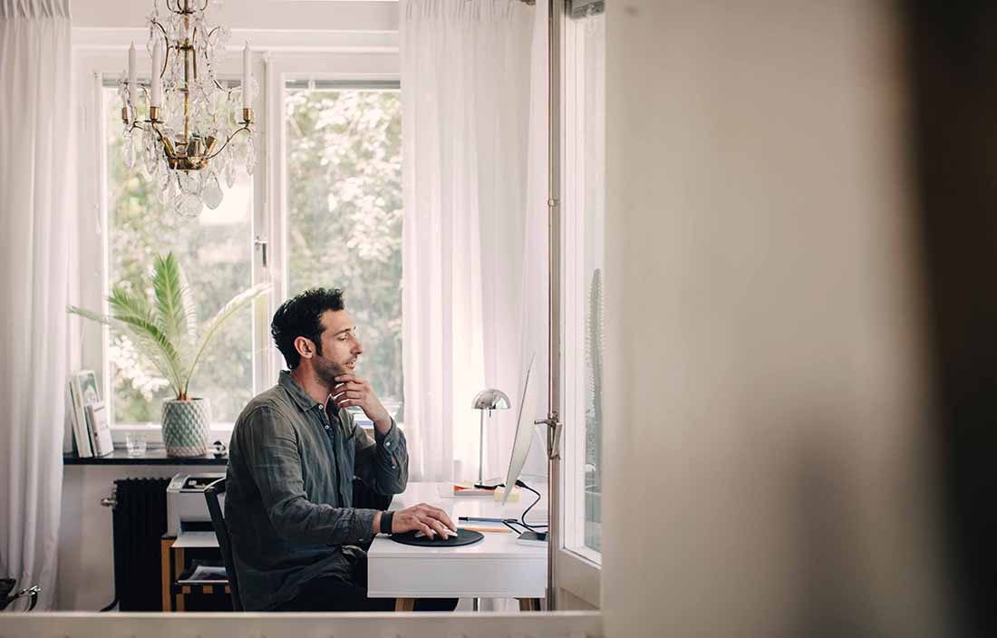 Man sitting at a desk, scrolling on a computer