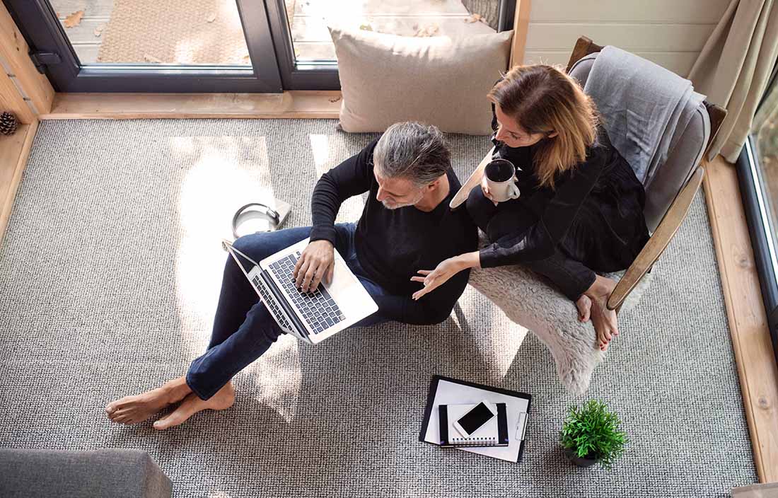 A man and a woman sitting in a living room looking at a laptop
