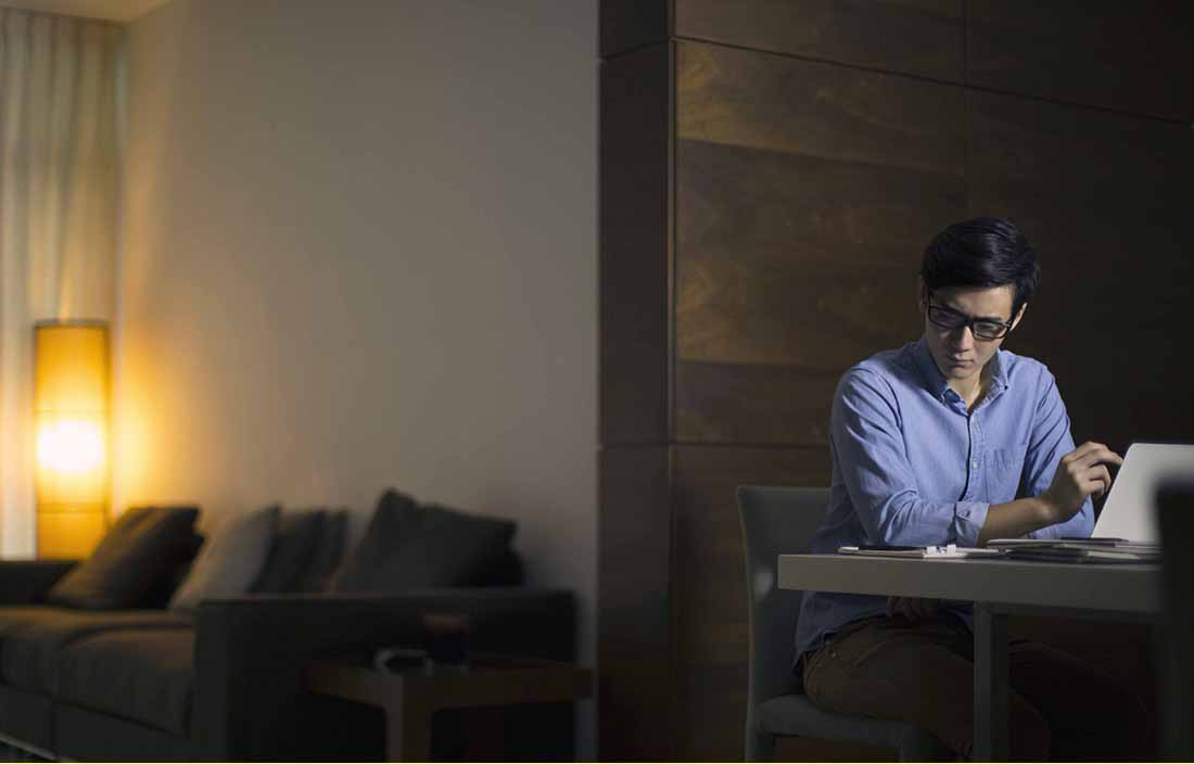 Man sitting in a dark room looking at his laptop