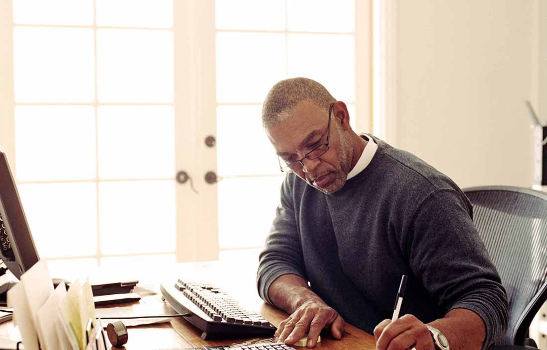 Business person working at their home office writing with a pen.