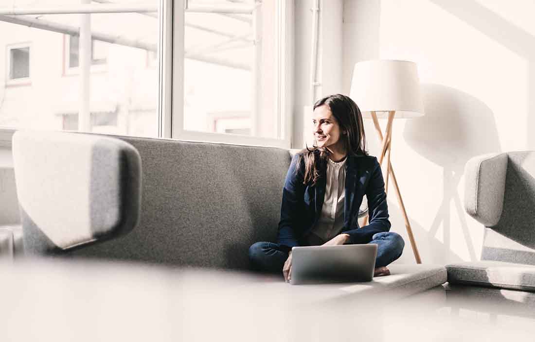 Woman sitting on couch with a laptop