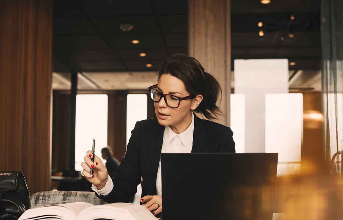 Businesswoman holding a pen over a book.