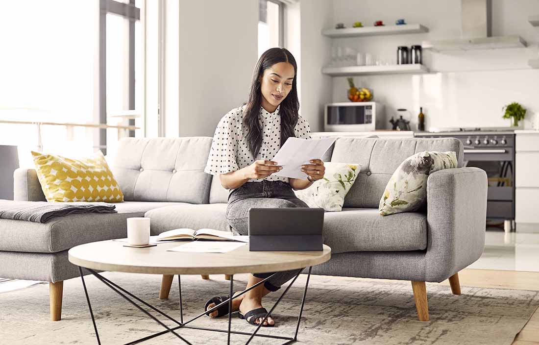 Businesswoman in a living room reviewing notes.