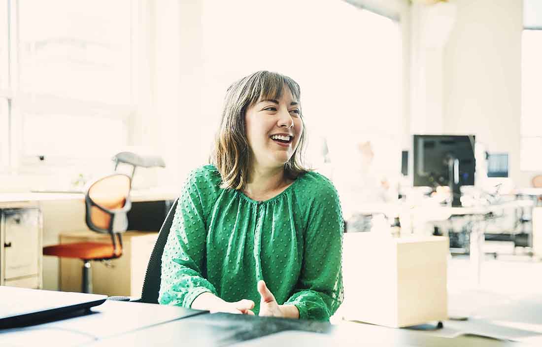 Businesswoman in casual clothing sitting at a desk in an office.