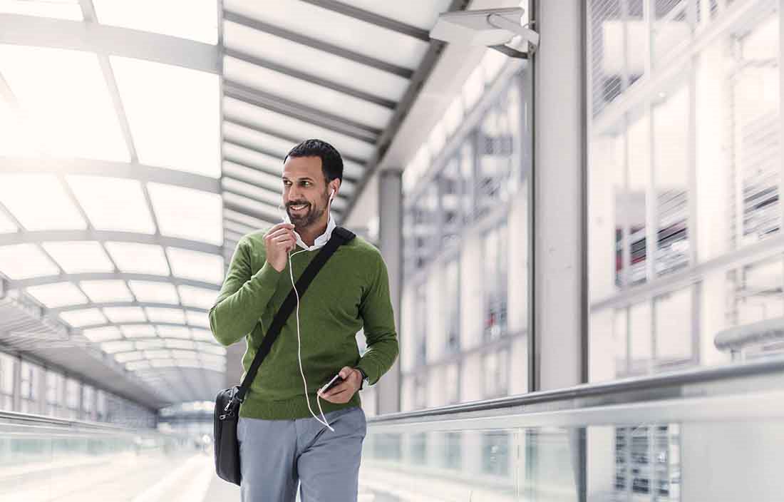 Business professional walking down a bridge walkway smiling.