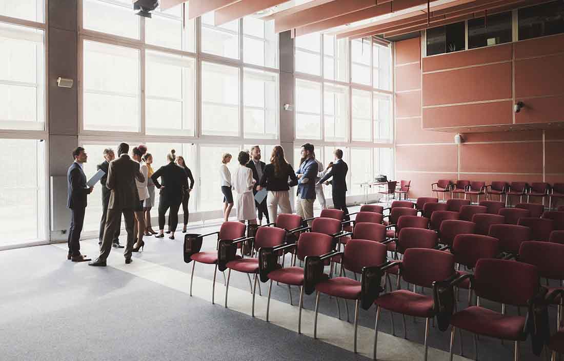 Conference attendees discussing amongst each other in a room.