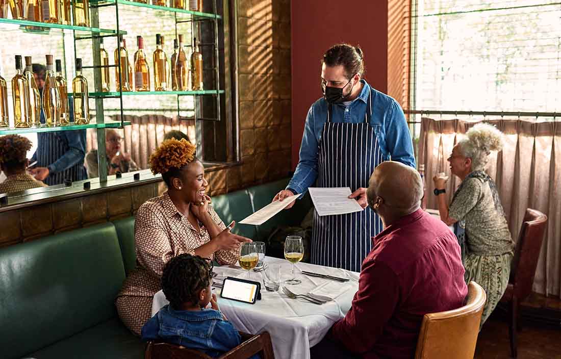 A waiter at a restaurant serving elderly patrons.
