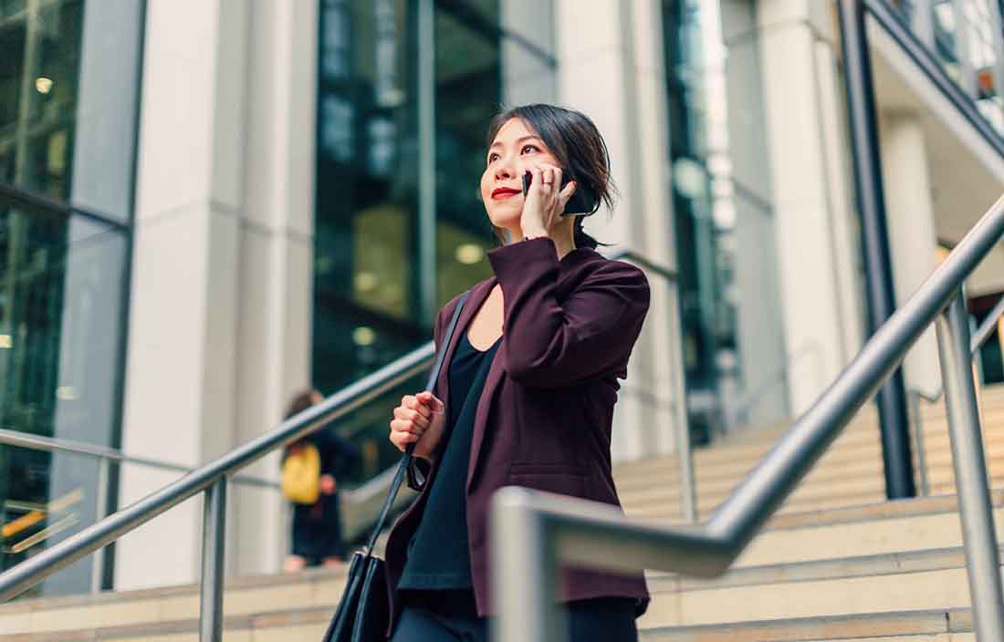 Insurance professional walking down some stairs taking a phone call.