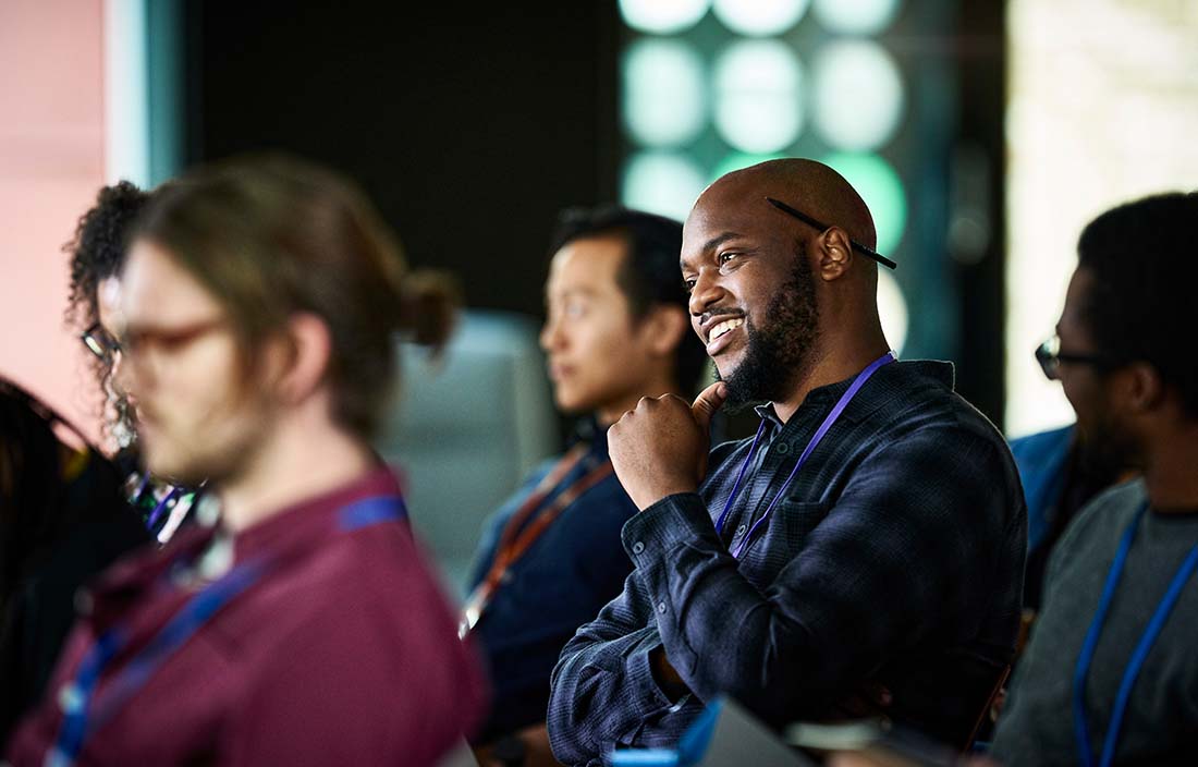 Business professionals listening to conference speaker.
