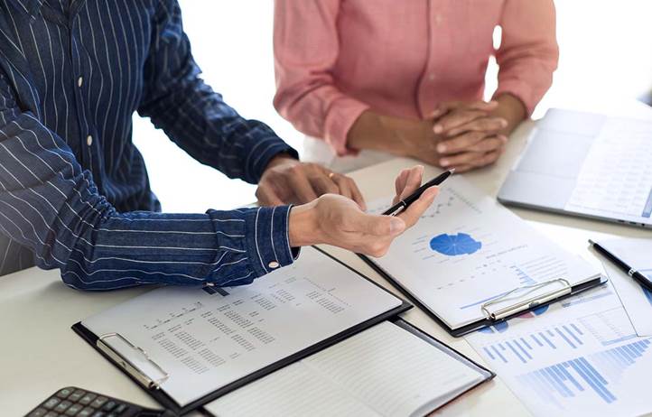 Reports laid out on a table in front of two businesspeople.