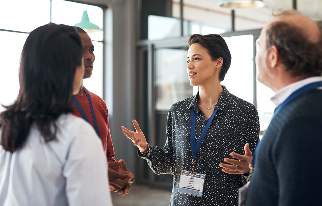 A photo of conference attendees discussing with one another.
