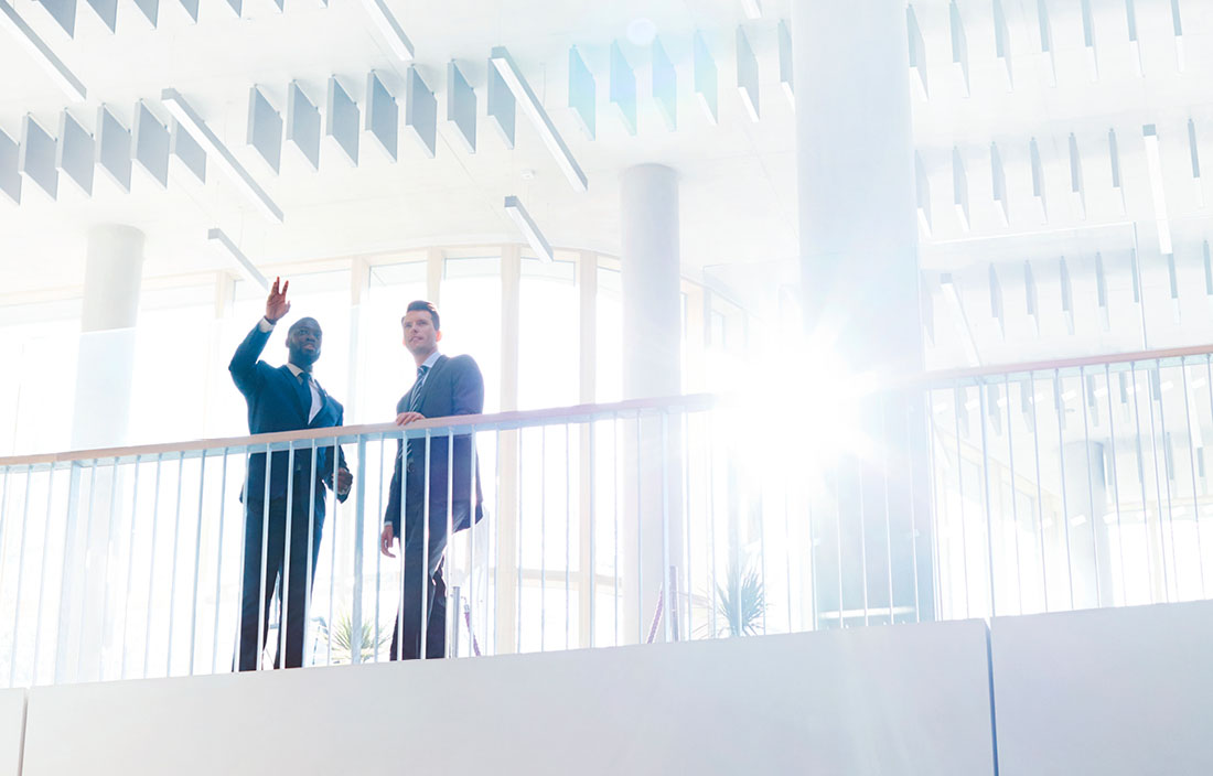 Two business professionals waving from balcony.