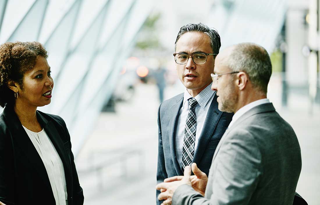 Group of business professionals talking outside.