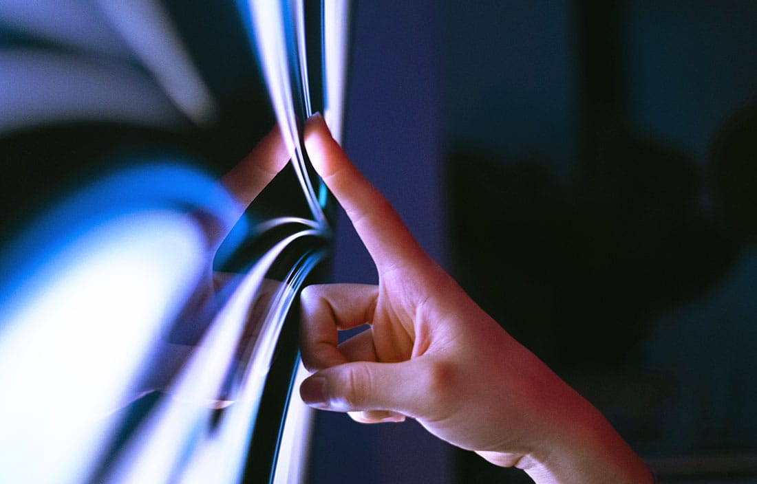 Hand touching computer screen.