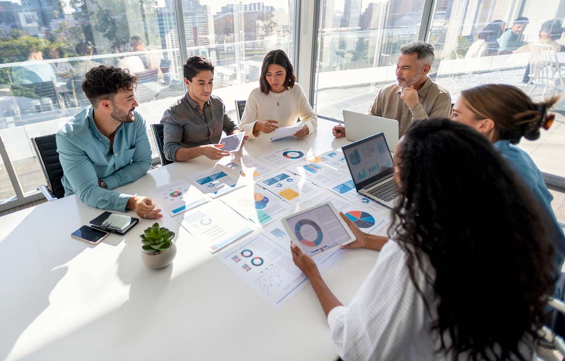 Business professionals sitting at a table discussing reducing benefit plan risk.