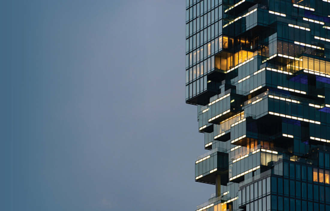 Modern luxury building lit up against night sky.