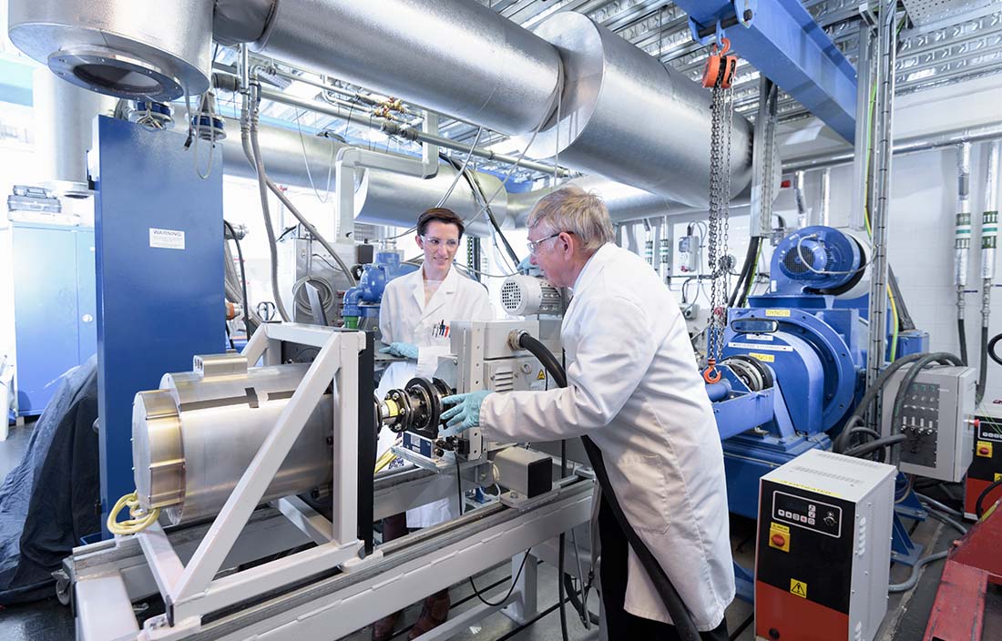 Photo of automotive workers in protective lab coats working with automotive machinery