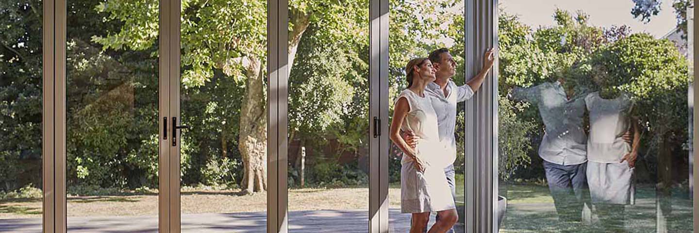 A couple standing next to a window in a home.