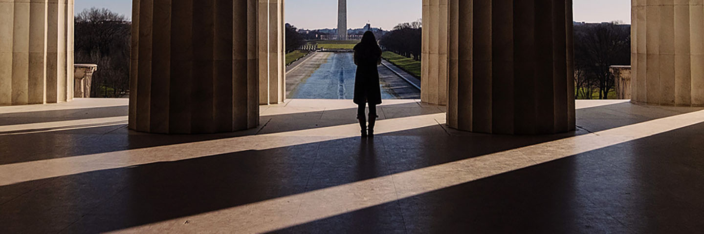 Close-up view of a person standing between marble columns at a government building site.