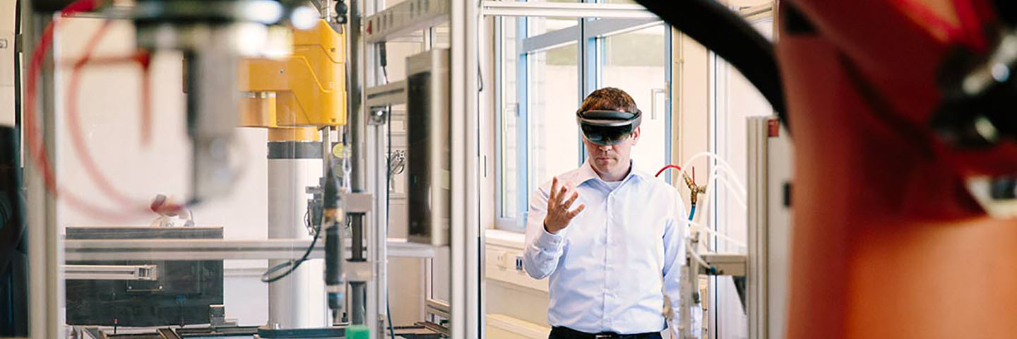 Manufacturing professional wearing a pair of VR goggles on a manufacturing floor.
