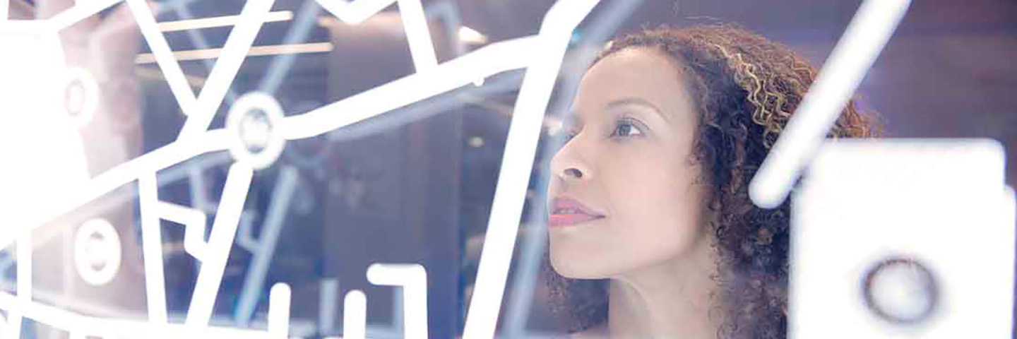 Business woman looking at information on a clear glass board.