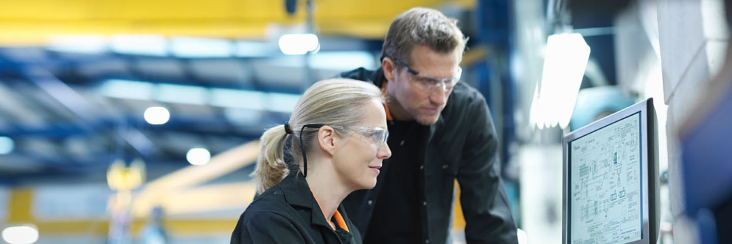 Two professionals looking at computer screen on manufacturing floor