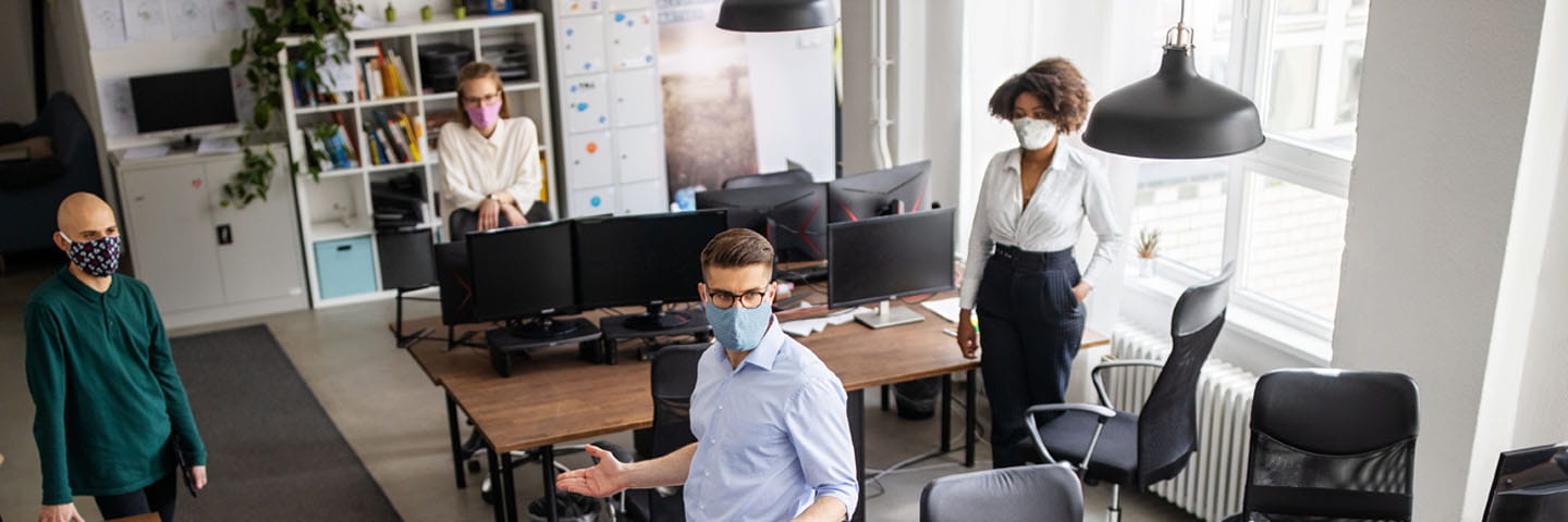 Business professionals in protective facemasks within the workplace.