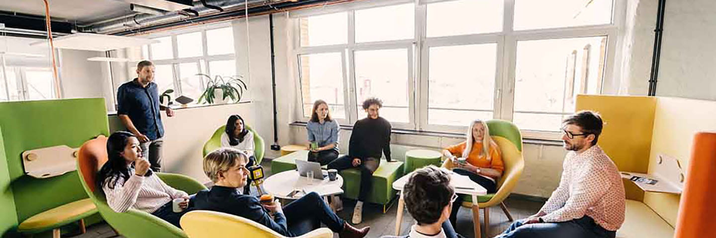 A group of business colleagues sitting in a modern meeting area brainstorming with one another.