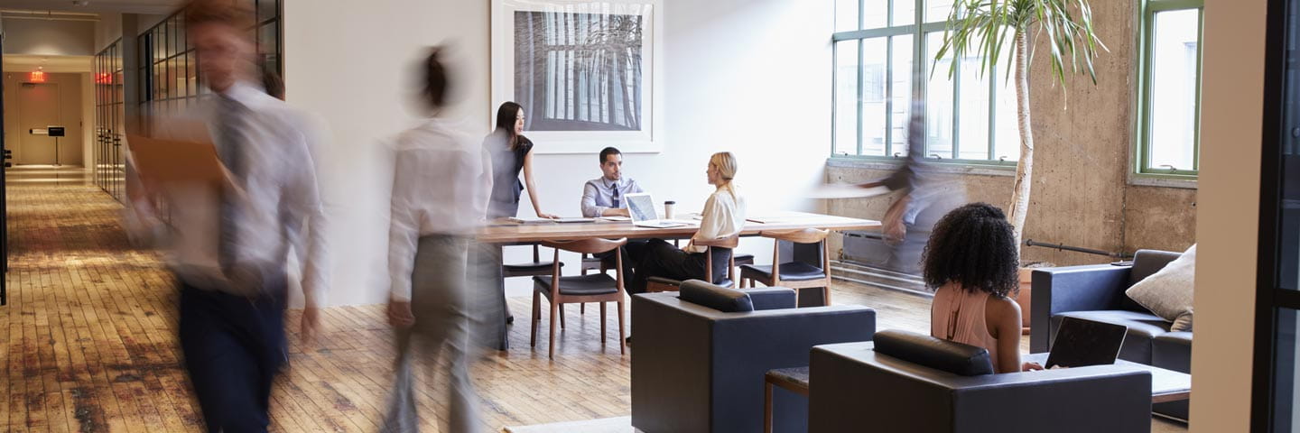 Image of a bustling modern office, with various seating options and staff doing in-person work
