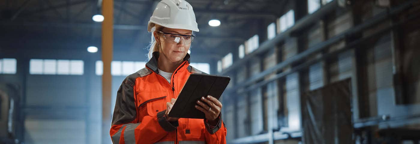Manufacturer looking at their tablet in a factory.