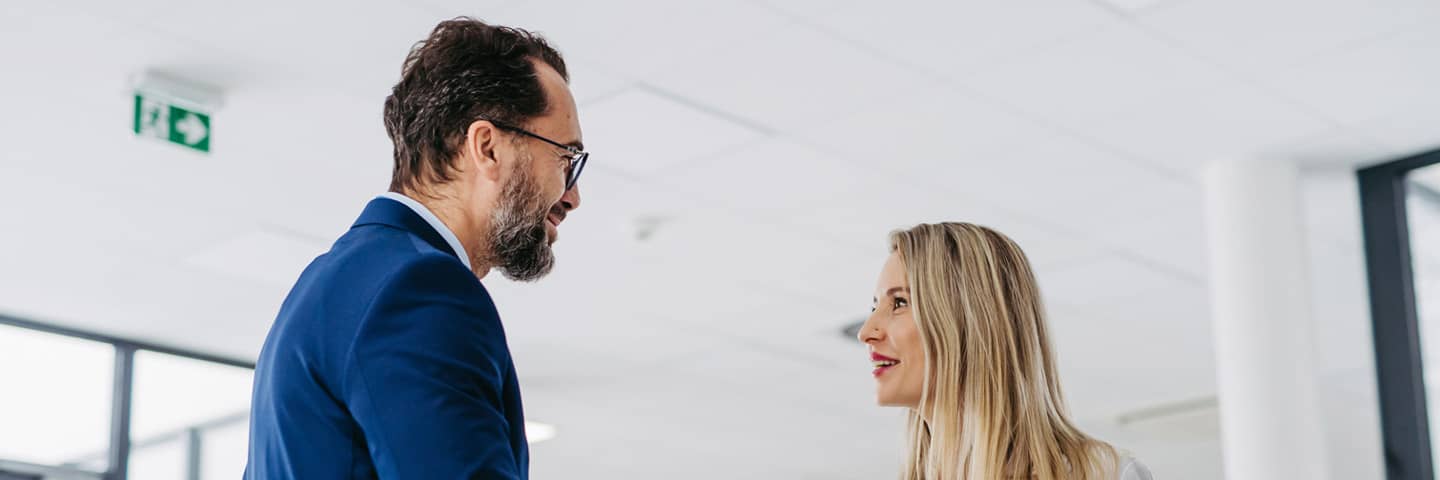 Two healthcare professionals talking to each other in a hospital hallway.