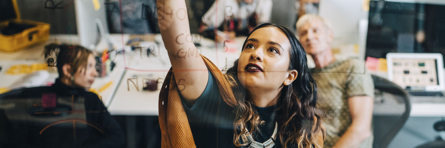 Person reaching up to write on whiteboard.