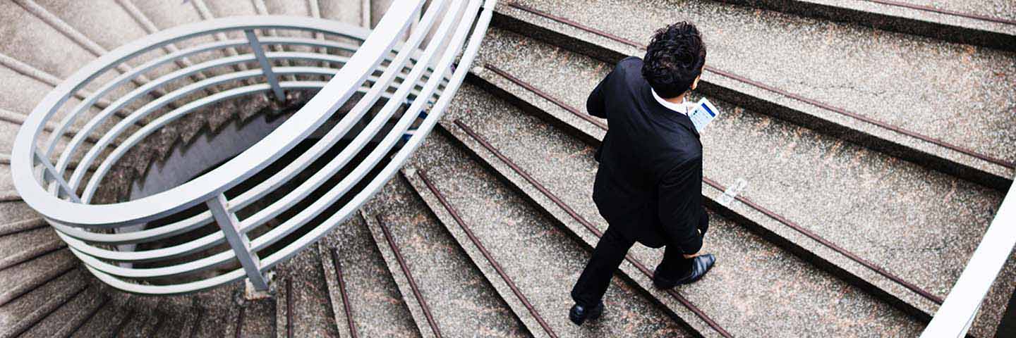 Person in business suit running up staircase.