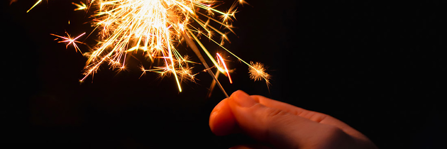 Hands holding a sparkler firework.