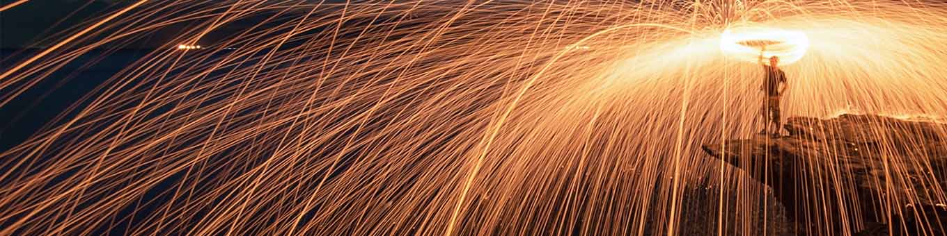 Man spinning fireworks on top of a cliff edge