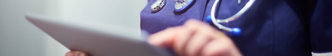 Close-up view of a doctors hand using a tablet device.