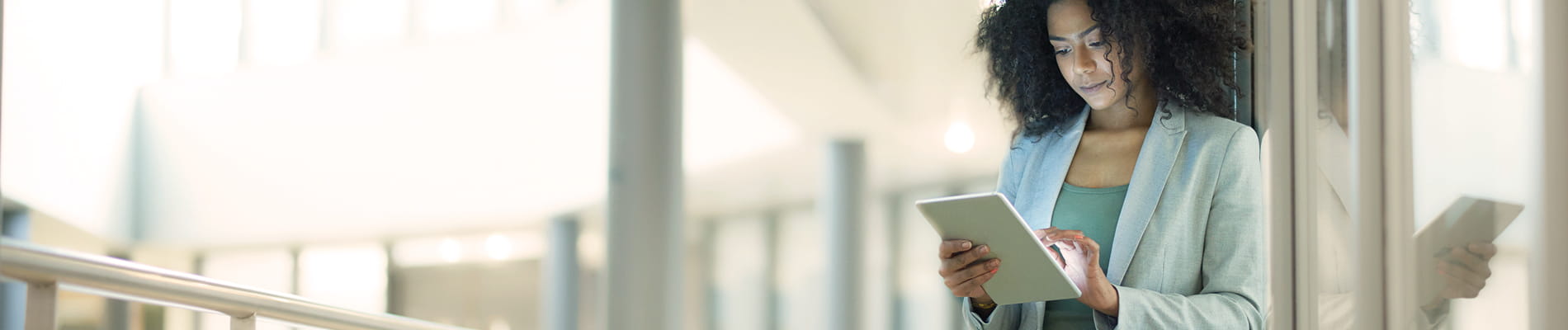 Woman standing by a wall looking at a tablet