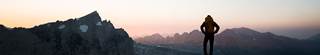 Backpacker summiting a mountain, looking out over a sunset.