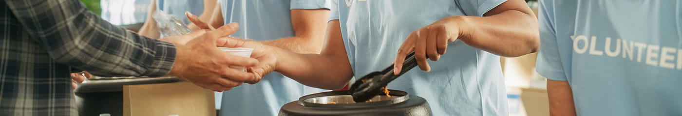 Volunteers working a soup kitchen on a sunny day.