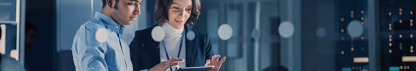 Two business professionals using a handheld tablet device together.