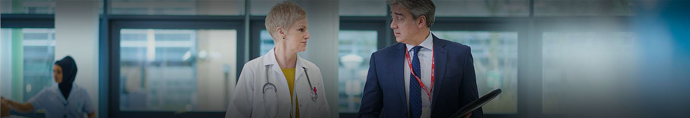Two doctors standing next to one another talking.
