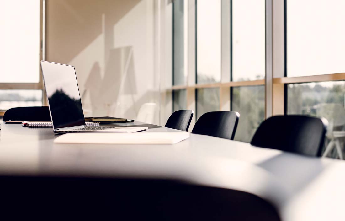 Close-up view of a laptop computer on a conference room table.