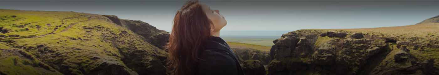 A woman standing in nature looking up into the sky.