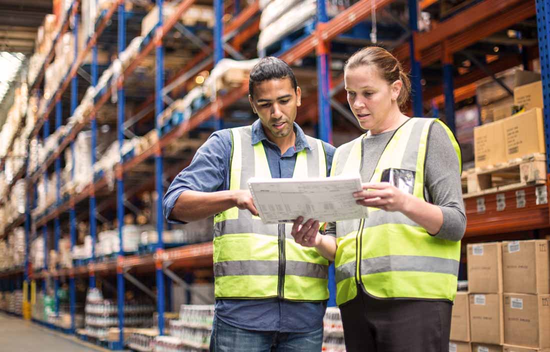 Two warehouse workers in yellow vests.