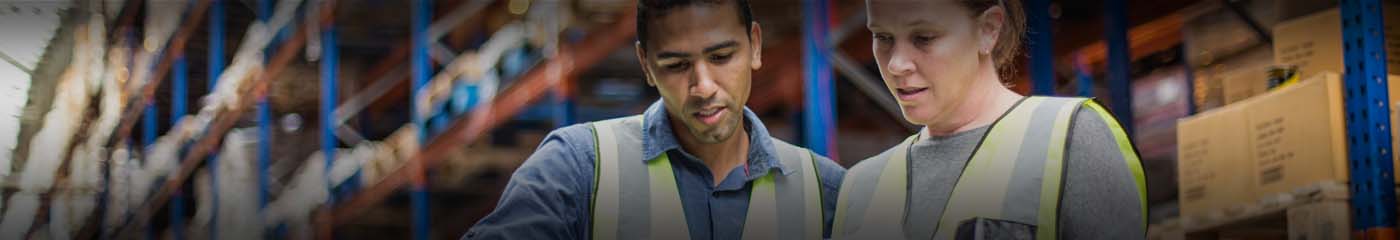 Two warehouse workers in yellow vests.