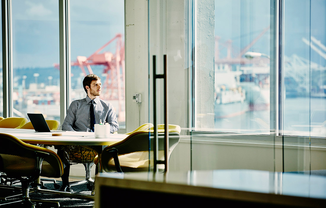 Business person sitting at his desk looking out the window.