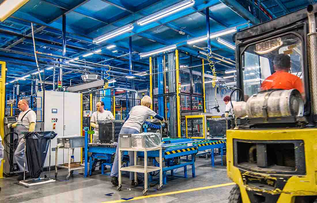 Workers in a manufacturing factory with a heavy machinery.