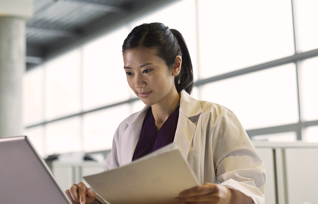 Asian doctor reviews medical notes.