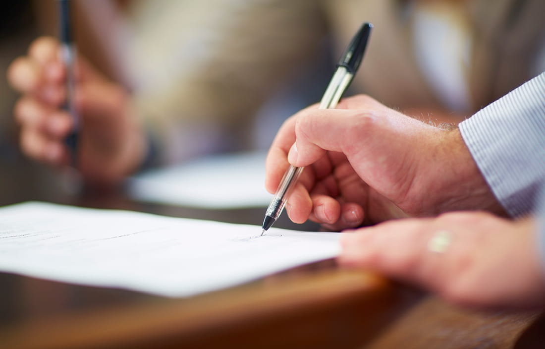 Man signing document with pen.