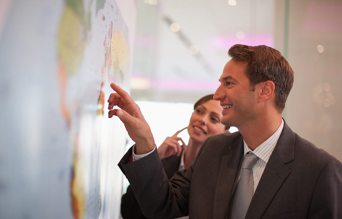 Man pointing to a location on a world map.